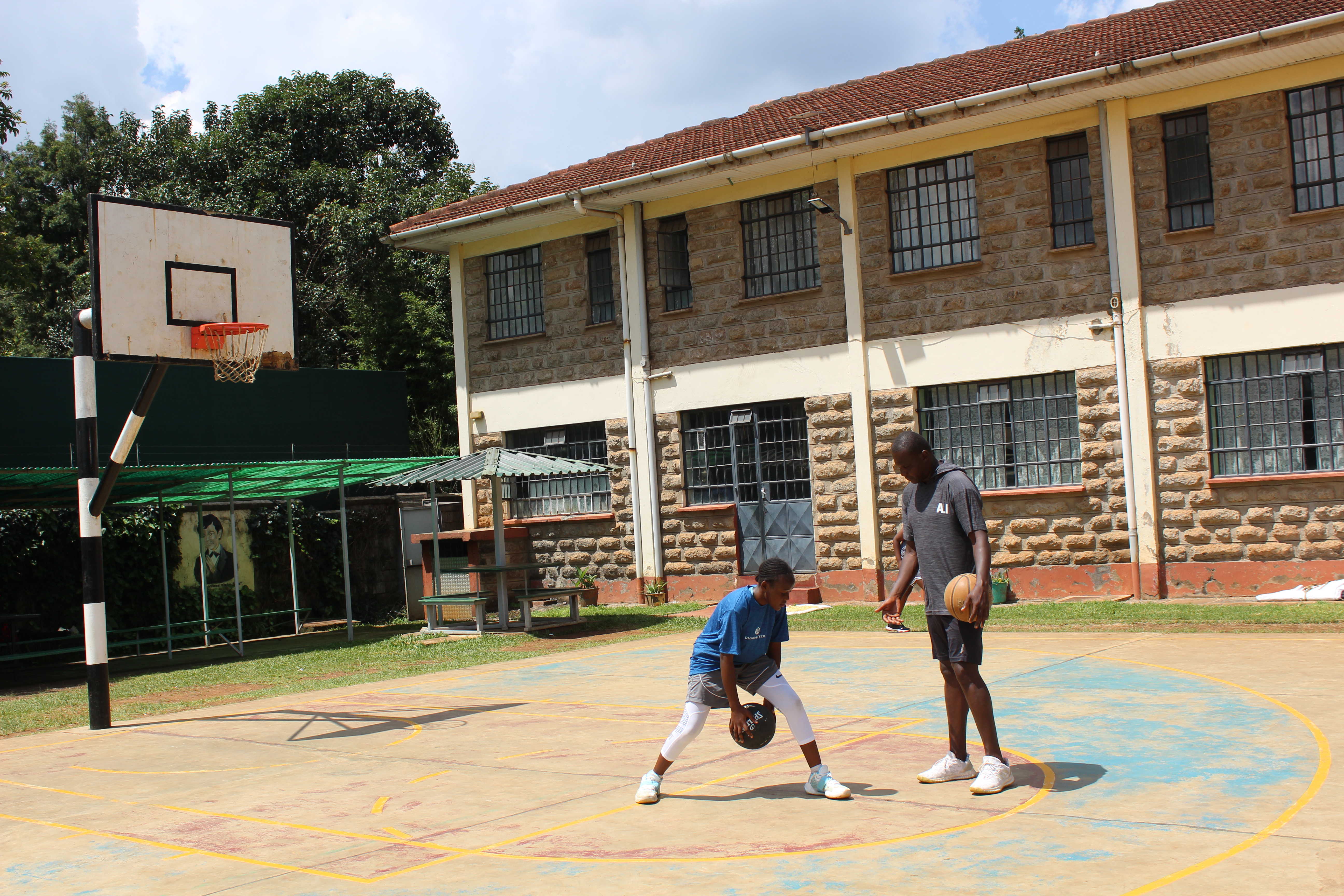 Coach supporting a young player during an outdoor basketball training session