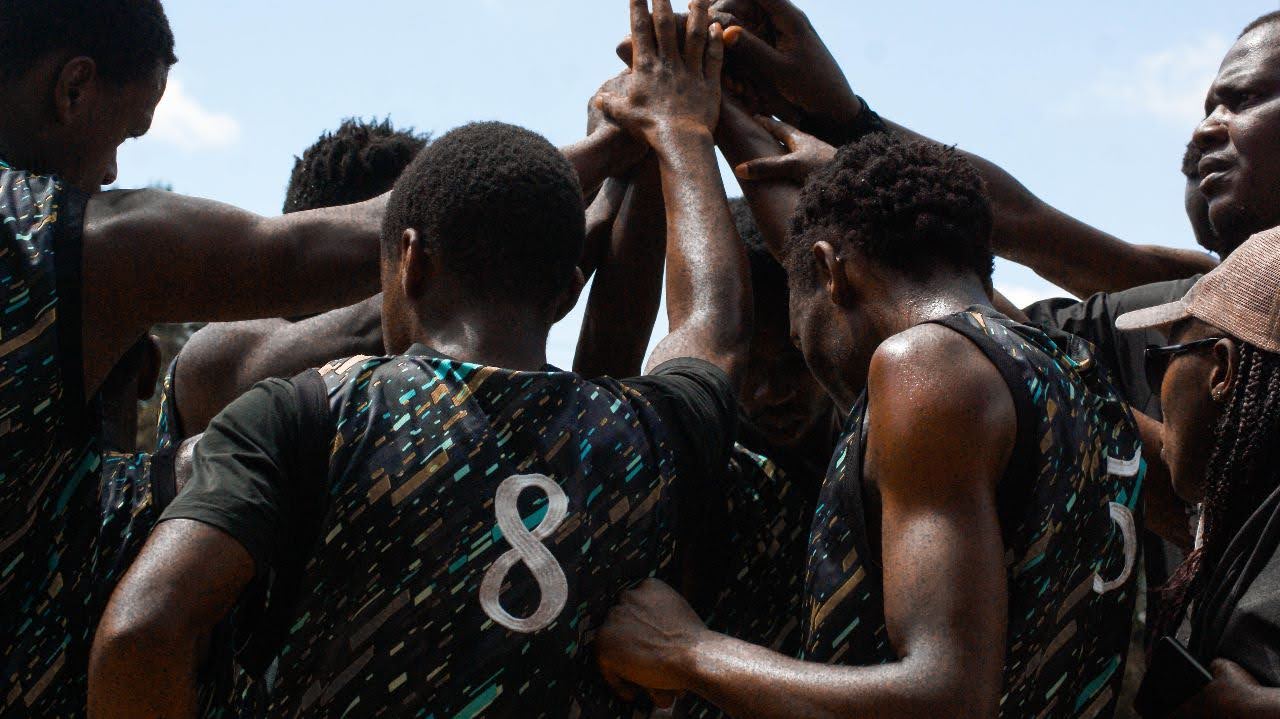 Basketball teammates bring their hands together in a team huddle