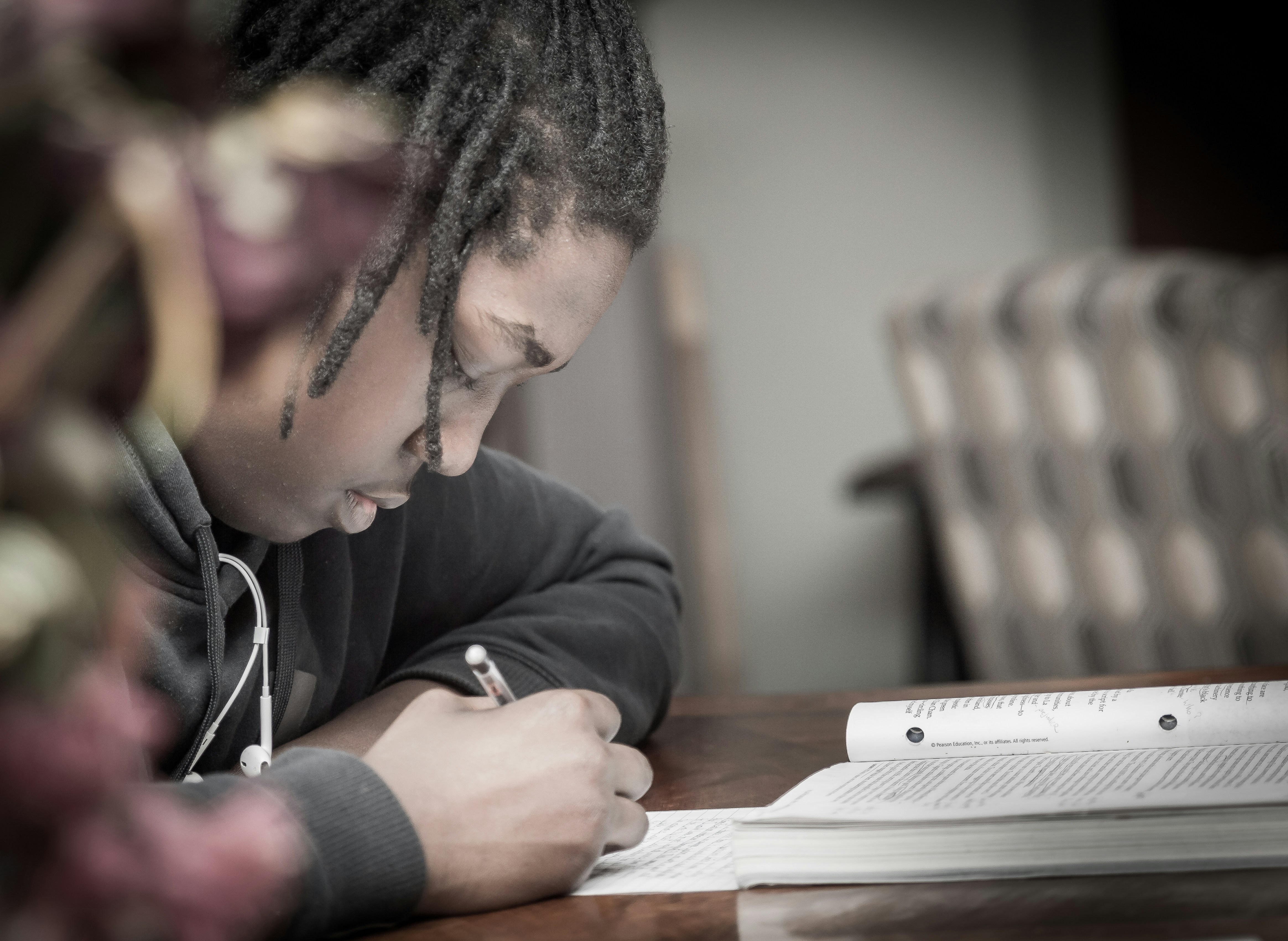 A young person studying and writing in a workbook